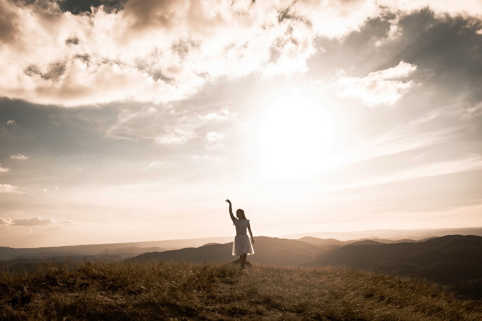 a woman standing on top of a grass covered hillside